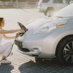 Femme accroupie charge sa voiture électrique