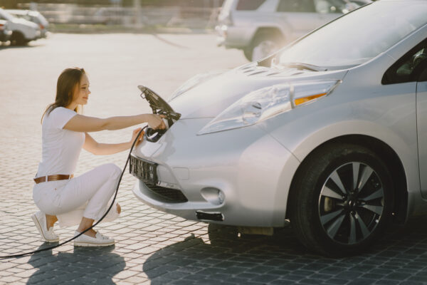 Femme accroupie charge sa voiture électrique